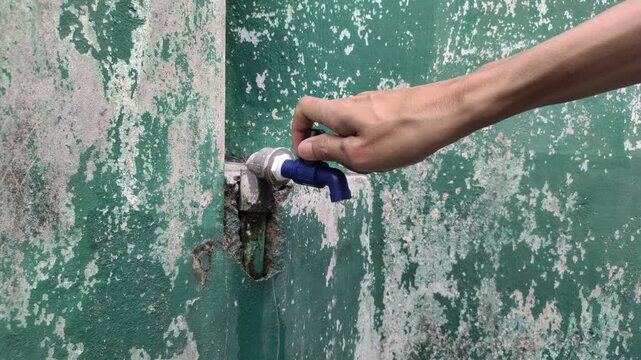 The person's right hand turns on the faucet until the water flows slowly, then turns off the faucet.