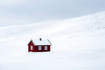 Small Red Cabin in a Snowy Landscape with Overcast Sky