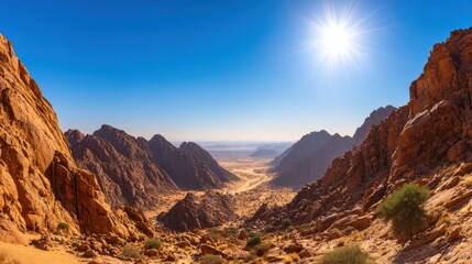 Naklejka premium Vast desert landscape with rocky mountains under a bright sun, showcasing natural beauty and serenity