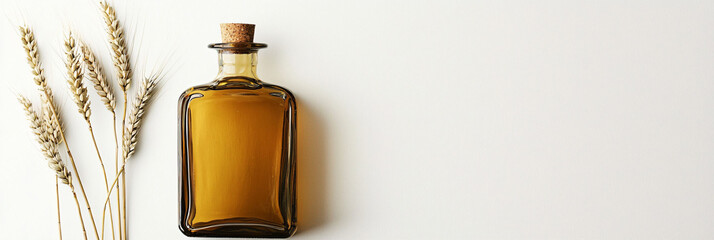 Glass Bottle with Olive Oil Next to Wheat Stalks on White Surface