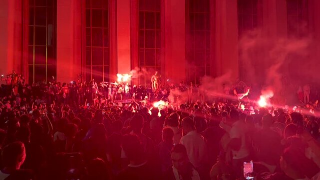 French football fans celebrating victory on the streets of Paris. Football soccer fans lit up the lights and smoke bombs. Crowd of furious people burning flares, screaming, dancing and singing anthem