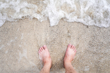 Barefeet of a man on the beach and sea