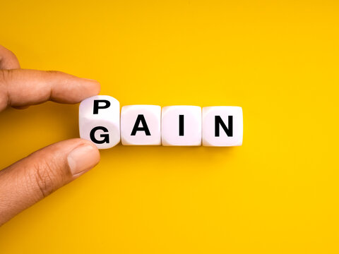 Hand flipping dice from pain to gain on yellow background symbolizes personal growth, mindset shift, overcoming challenges, success through effort, motivation, and positive change in business or life.