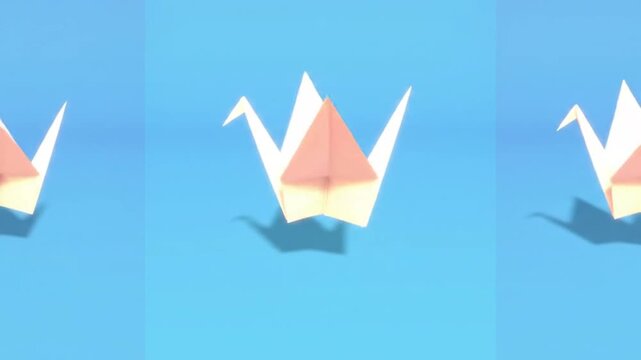 Three Origami Paper Cranes Floating Against a Bright Blue Sky