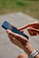 Woman using smartphone. Close-up of female hand holding modern mobile phone outdoors in daylight. Using technology in daily life and communication concept