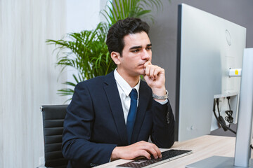 Young Businessman or Programmer looking worried and stressed over working on a computer code at...