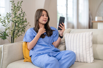 Woman doctor using smartphone for remote work, conducting video call consultation to provide health...