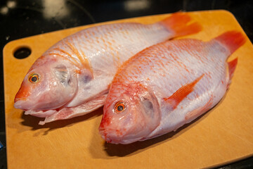 Red tilapia on a wooden cutting board ready for preparation and cooking