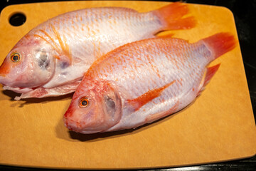Red tilapia on a wooden cutting board ready for preparation and cooking