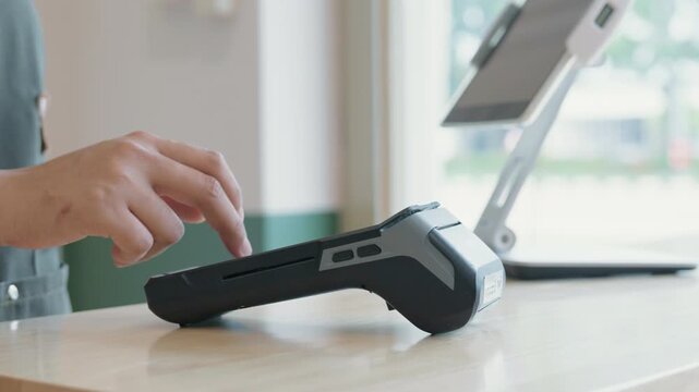 Close-up hand of a customer tapping credit card with a payment terminal or credit card machine at a cashier in a restaurant. cashless payment, card reader, electronic funds transfer