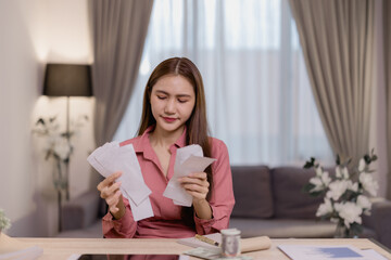 Young woman managing monthly expenses and debt, reviewing financial documents, analyzing invoices,...