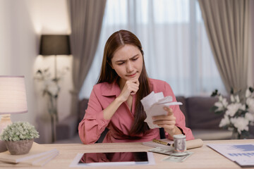 Young asian businesswoman looking stressed and worried about her bills, having financial problems...