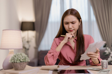 Worried woman managing monthly expenses and calculating bills while reviewing household finances,...