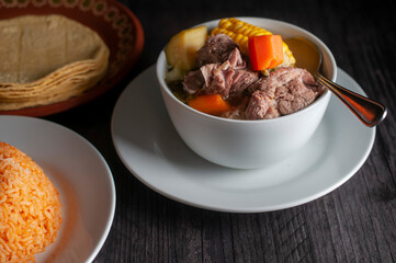  Beef rib broth with corn and carrots on a table with Mexican rice and corn tortillas, 45 angle ...