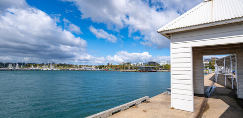 Panoramic view from Cunningham Pier in Geelong, Australia, with timber pavilion overlooking Corio Bay and marina. Concept of coastal landmark, recreational waterfront, regional tourism destination.