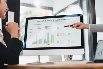 Quarterly business growth performance presentation on desktop monitor with colleagues discussing colorful bar chart and infographic in modern office, collaborative meeting and analytical focus