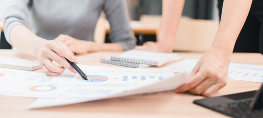 Business meeting with colleagues reviewing financial chart and pie chart data, collaborative planning and analysis with pen and documents conveying focused teamwork and productive discussion