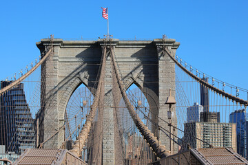 Obraz premium waving american flag above the pillars of the brooklyn bridge a symbol of new york city