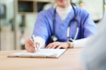 Nurse writing patient notes on clipboard while consulting with patient, focused medical documentation and compassionate communication