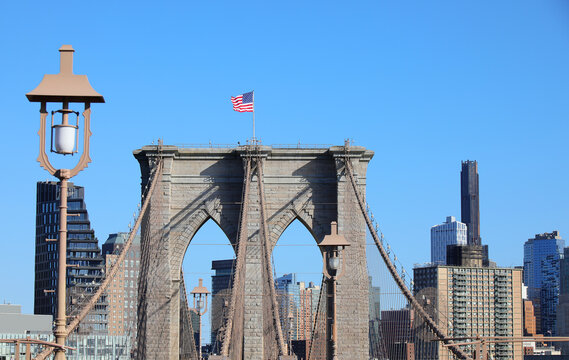 waving american flag above the pillars of the brooklyn bridge a symbol of new york city and the american identity - Powered by Adobe