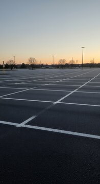 Empty parking lot with white lines under a clear sky at dusk.