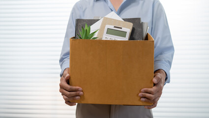 Business man sending resignation letter and packing Stuff Resign Depress or carrying business cardboard box by desk in office. Change of job or fired from company