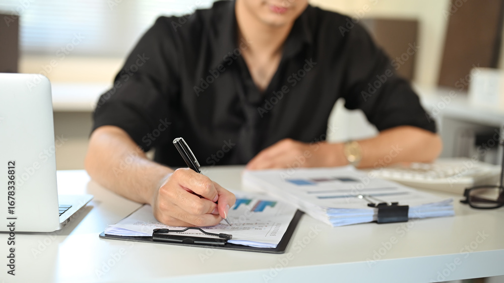 Poster office worker analyzing business charts and making corrections on paper reports
