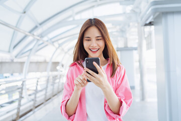 Young Asian woman using social media on smartphone in a urban city. fast connection, checking...
