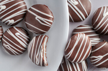 Chocolate-covered mint cookies on a white plate, high-sugar foods that are unhealthy carbohydrates. top view or flat lay