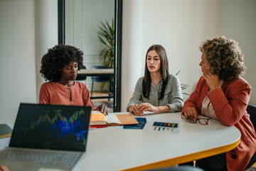 Businesswomen discussing financial charts and data at office meeting