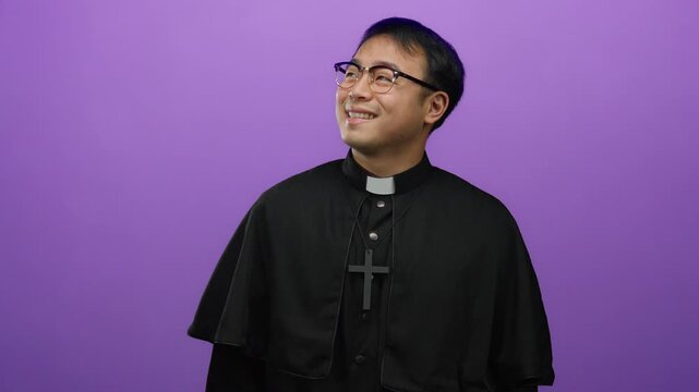 Man priest smiling wearing black robe and cross necklace with glasses against vibrant purple background representing religious theme