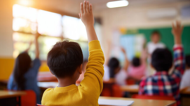 Children raising their hands in a classroom while a teacher stands in front of the chalkboard.