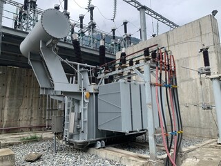 A large, high-voltage electrical transformer stands at an outdoor substation. The industrial...