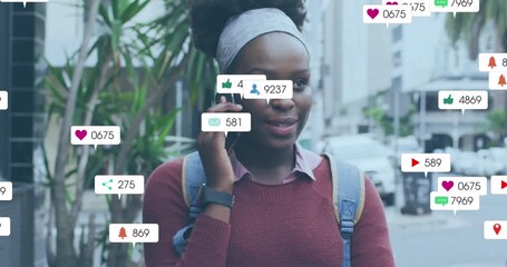 Animation of multiple social media icons over african american woman talking on smartphone outdoors - Powered by Adobe