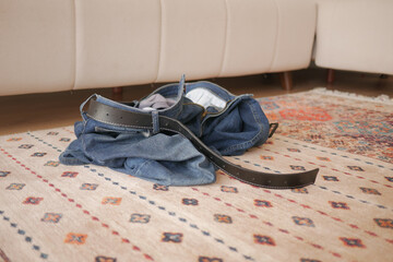Jeans and belt casually strewn on a living room floor