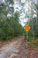 Road closed ahead safety sign on a lonely rural dirt road; vertical format.
