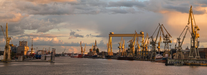 Beautiful storm clouds illuminated by the setting sun over the shipyard in Szczecin, Poland