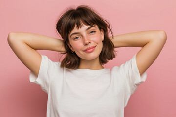 Fototapeta premium Young woman tilting head slightly with gentle smile, hands relaxed by sides, soft surprised expression, simple pastel pink background