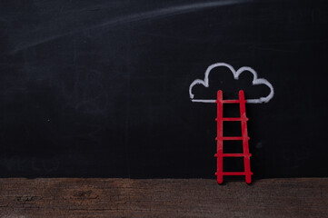 Wooden ladder leaning on blackboard with chalk drawn cloud