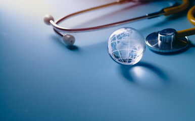 Glass global and stethoscope on light blue background, earth day, world health day, medical and...