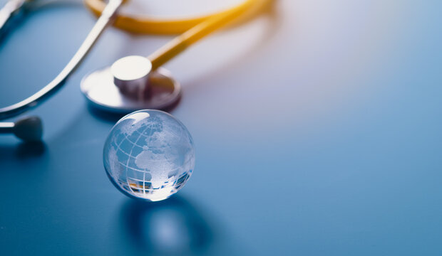 Glass global and stethoscope on light blue background, earth day, world health day, medical and healthcare business technology concept