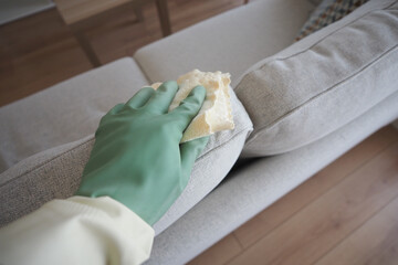Cleaning a sofa with gloves in a modern living room