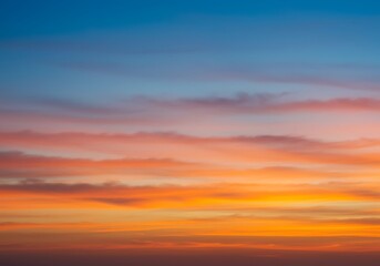 Fototapeta premium A beautiful, vibrant sunset sky with clouds in a smooth gradient of orange, pink, and blue