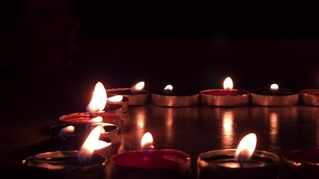 Burning candles against full dark background with copy space. Candles are used on occasions such as birthdays, weddings, festivals, prayers, and memorials to create light, symbolize devotion