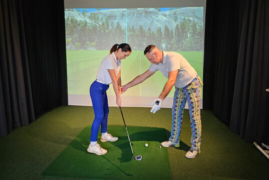 Golf instruction session with a coach and a student at an indoor simulator