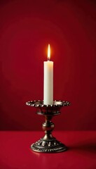 Ornate candle holder with lit candle on deep red backdrop, winter, object, macro