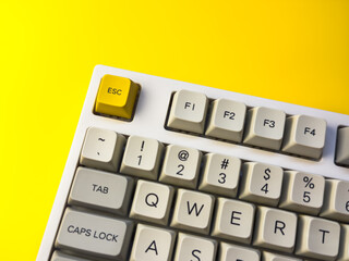 White mechanical keyboard with bright Esc key on bright yellow background, minimalism, keyboard...