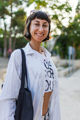 Portrait of a young girl on a sunny city street. The girl smiles and looks at the camera. Urban...