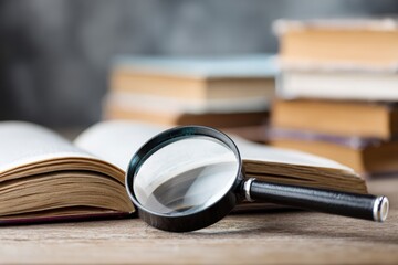 Open book with magnifying glass on wooden table