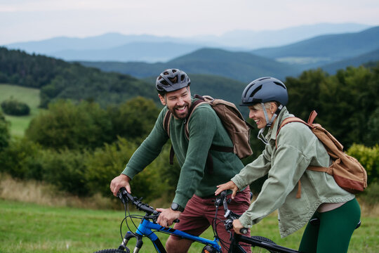 Couple cycling together in nature, smiling and enjoying outdoor adventure. - Powered by Adobe